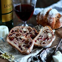 two slices of bread with fruit and nuts on them next to a glass of wine