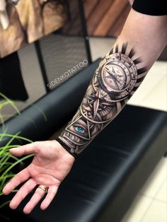 a man's arm with a compass tattoo on it and his hand in the foreground