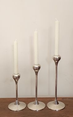 three silver candles are on a wooden table