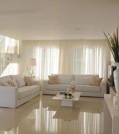 a living room filled with white furniture and lots of windows