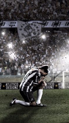 a soccer player sitting on the ground in front of a stadium full of people watching