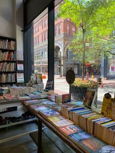 a table with books on it in front of a window that has a view of the street