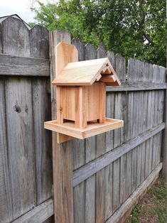 a wooden bird house hanging on the side of a fence