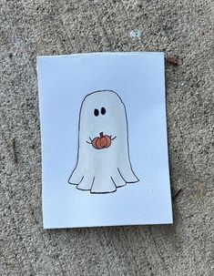 a piece of paper with a drawing of a ghost holding a pumpkin in it's mouth