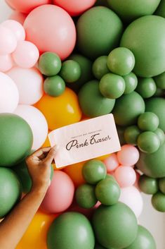 a person holding up a sign in front of balloons