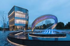 the building is lit up at night and has a circular fountain in front of it