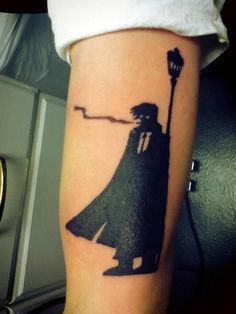 a man with a hat and cape on his arm is holding a lamppost tattoo