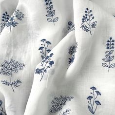 a white and blue flowered fabric with dark blue flowers on the top, in close up