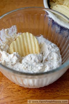 a bowl filled with dip and chips on top of a wooden table