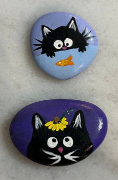 two painted rocks with black cats on them