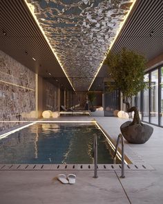 an indoor swimming pool in a modern building with stone walls and ceiling lights above it