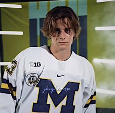 a young man wearing a jersey with the letter m on it