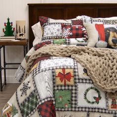 a bed covered in blankets and pillows next to a table with christmas decorations on it