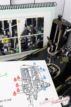 an old sewing machine and manual on a table next to a notebook with instructions for how to sew