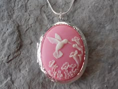 BEAUTIFUL LOCKET.  HUMMINGBIRD (IVORY/ ON A PERFECT PINK BACKGROUND.  BEAUTIFULLY DETAILED. SET IN A GORGEOUS SILVER PLATED LOCKET, HOLDS TWO PICTURES ON THE INSIDE, OR A KEEPSAKE. VERY UNIQUE AND VERY PRETTY.  2" LONG by 1 1/2" WIDE ON A 22" .925 SILVER PLATED SNAKE CHAIN 1.2mm WITH LOBSTER CLAW CLASP.  VERY NICE QUALITY.  PASS DOWN FROM GENERATION TO GENERATION.  MAKES A WONDERFUL GIFT, AT A REASONABLE PRICE. PLEASE SEE MT OTHER ITEMS,(SEE THE MATCHING BROOCH/PIN)  I MAKE SEVERAL DIFFERENT CAMEO NECKLACES, BRACELETS, BROOCHES AND MATCHING SETS. AS WELL AS MANY, MANY DIFFERENT BUFFALO NICKEL NECKLACES, AND OTHER COIN NECKLACES, ALL AT VERY REASONABLE PRICES.  SOMETHING FOR EVERYONE ON YOUR LIST, ONE STOP SHOPPING AND FREE SHIPPING. THANKS FOR LOOKING. Froo www.froo.com | Froo Cross Sell, Pink Pendant, Pendant Locket, Cameo Jewelry, Dope Jewelry, Cameo Pendant, Funky Jewelry, Jewelry Lookbook, Perfect Pink, Coin Necklace