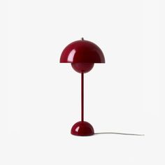 a red lamp sitting on top of a white floor next to a light bulb in the shape of a mushroom