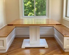 an empty room with wooden flooring and white walls, along with a window overlooking the trees