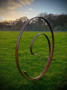 a metal sculpture in the middle of a grassy field