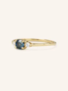 a yellow gold ring with an oval blue sapphire and two small diamonds on the side