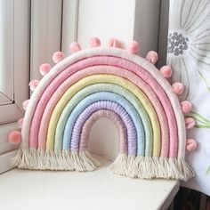 a rainbow shaped pillow sitting on top of a window sill