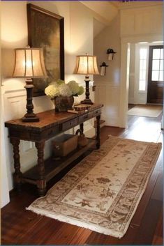 a hallway with two lamps and a rug on the floor in front of an entryway