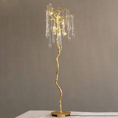 a gold colored floor lamp with crystal beads on it's base and a white table cloth underneath