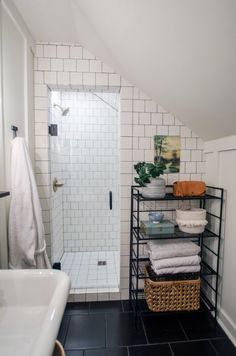 a bathroom with black tile flooring and white tiles on the walls, along with shelving