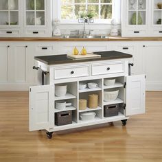 a white kitchen island with black top and drawers on wheels in front of a window