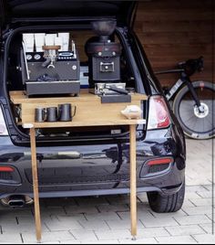 the back end of a car with a coffee maker on it's table in the trunk