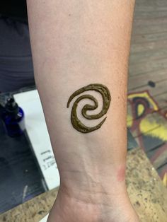 a small tattoo on the wrist of a person's left arm, which is shaped like a spiral