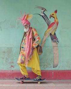 an old man is standing on a skateboard in front of a wall with birds painted on it