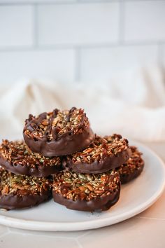 chocolate covered donuts with sprinkles and nuts on a white platter