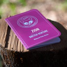 a pink notebook sitting on top of a tree stump