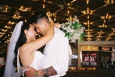 a bride and groom embracing each other in the middle of a room with lights overhead