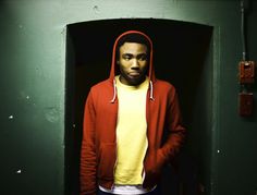 a man wearing a red hoodie standing in a doorway