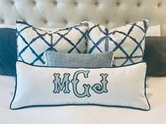 pillows with monogrammed letters on them are sitting on a bed in front of a tufted headboard