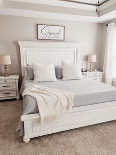 a white bed sitting in a bedroom on top of a carpeted floor next to a window