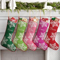 christmas stockings hanging from a mantel decorated with snowflakes and personalized names