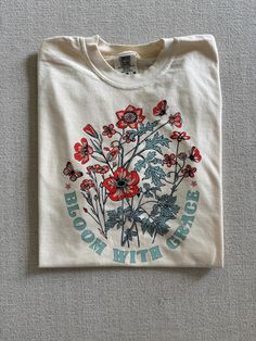 A gentle reminder to Bloom with Grace 🌸🌷Some seasons in life can be tough but the flowers always bloom after the rain ❤️ Preshrunk 100% cotton tees.  We recommend sizing up to get that oversized look.  Unisex fit (see size chart)  🌀WASHING INSTRUCTIONS ✅Turn shirts inside out prior to washing.  ✅Machine wash cold with like colors.  ✅Hang dry for best care or tumble dry on low.  ❌Do not iron.  ❌Do not use chlorine bleach.  ❌Do not dry clean.  Each shirt is made to order and hand pressed. We do Spring Organic Cotton Tops With Graphic Print, Spring Organic Cotton Graphic Print Tops, Spring Cotton T-shirt With Graphic Print, Spring Organic Cotton T-shirt For Everyday, Oversized Organic Cotton Tops For Spring, Spring Letter Print Cotton T-shirt, Spring Cotton T-shirt With Letter Print, Oversized Screen Print T-shirt For Spring, Organic Cotton Graphic Print T-shirt For Spring