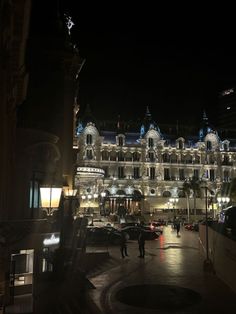 a very tall building with lots of lights on it's sides and people walking down the street