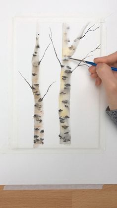 someone is using scissors to cut out birch trees on the paper and paint them with watercolors