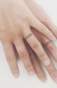 two fingers with roman numerals tattooed on them