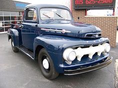 an old blue truck is parked in front of a building with a sign that says,