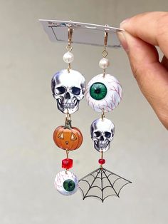 Add a spooky, playful touch to your Halloween outfit with these handmade statement earrings! Designed and crafted with intricate details, these earrings feature a unique combination of Halloween icons--eyeballs, skulls, pumpkins, bats, and spiderwebs. Each pair showcases multiple charms for a bold, festive look. The earrings are carefully handmade for a vibrant, detailed finish. The hardware is 18k gold-plated and hypoallergenic, ensuring comfort and safety for sensitive ears. Perfect for Hallow Spooky Handmade Earrings For Halloween, Handmade Spooky Halloween Earrings, Spooky Handmade Halloween Earrings, Handmade Skull Earrings For Halloween, Whimsical Halloween Earrings, Spooky Halloween Drop Earrings, Whimsical Handmade Earrings For Halloween, Whimsical Handmade Halloween Earrings, Earrings Halloween