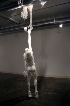 a white sculpture hanging from the ceiling in an empty room