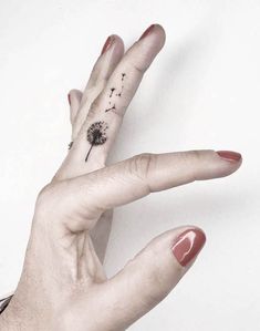 a woman's hand with a dandelion tattoo on it