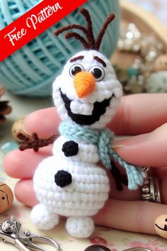 a hand holding a small crocheted snowman ornament