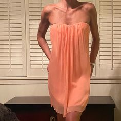 A Gorgeous Pale Coral Strapless Dress. It Has A Sweetheart Bust Line With A Center Draped Pleating That Creates A Flowing Line Down The Middle. Has Boning With An Elastic Bra-Like Closure In The Back With An Exposed Zipper Under The Open Back. Has A More Satiny Lining And It Is Brand New With Tags. Flowy Strapless Mini Dress For Date Night, Flirty Peach Sleeveless Mini Dress, Peach Strapless Dress For Summer, Peach Strapless Summer Dress, Sleeveless Peach Dress For Date Night, Peach Sleeveless Dress For Date Night, Summer Peach Strapless Dress, Pink Flowy Mini Dress With Sweetheart Neckline, Peach Sleeveless Flirty Dress