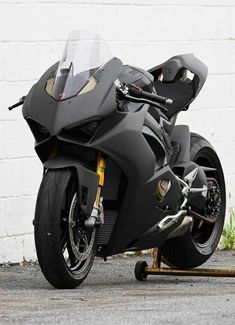 a black motorcycle parked next to a white brick wall