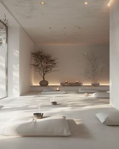 an empty room with white walls and flooring is lit by candles in vases